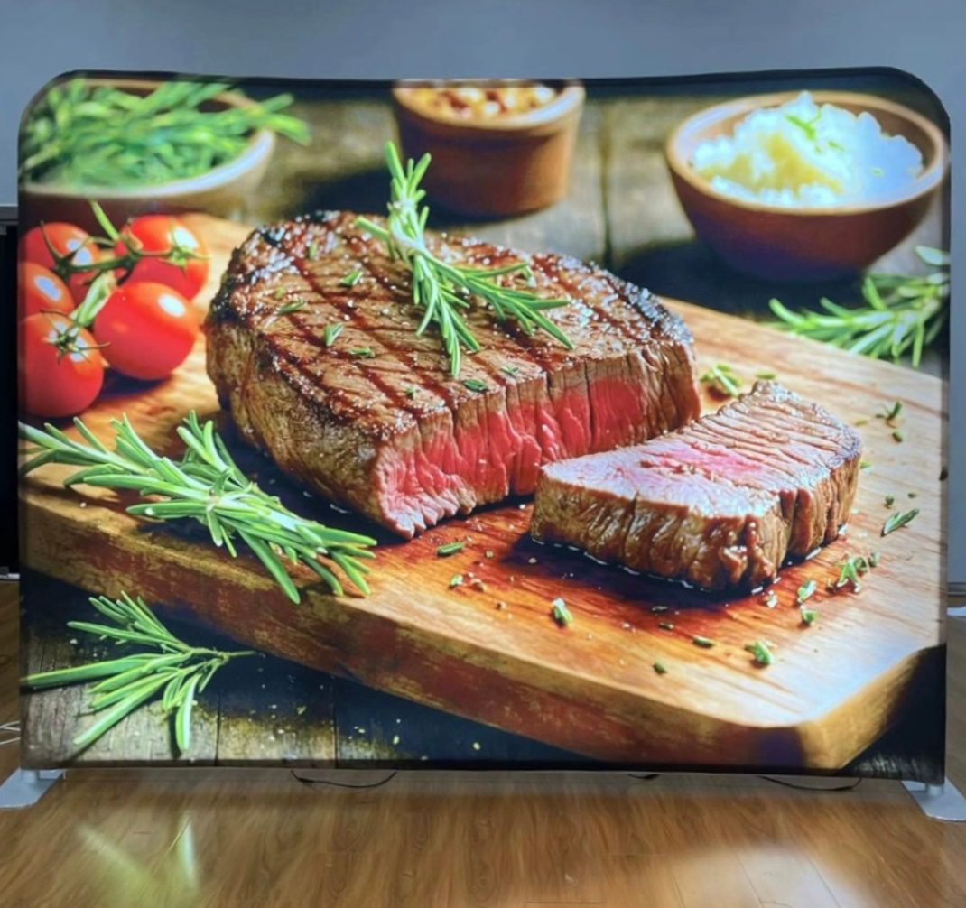 Backlit tension fabric display with vivid food photography, lit edge to edge